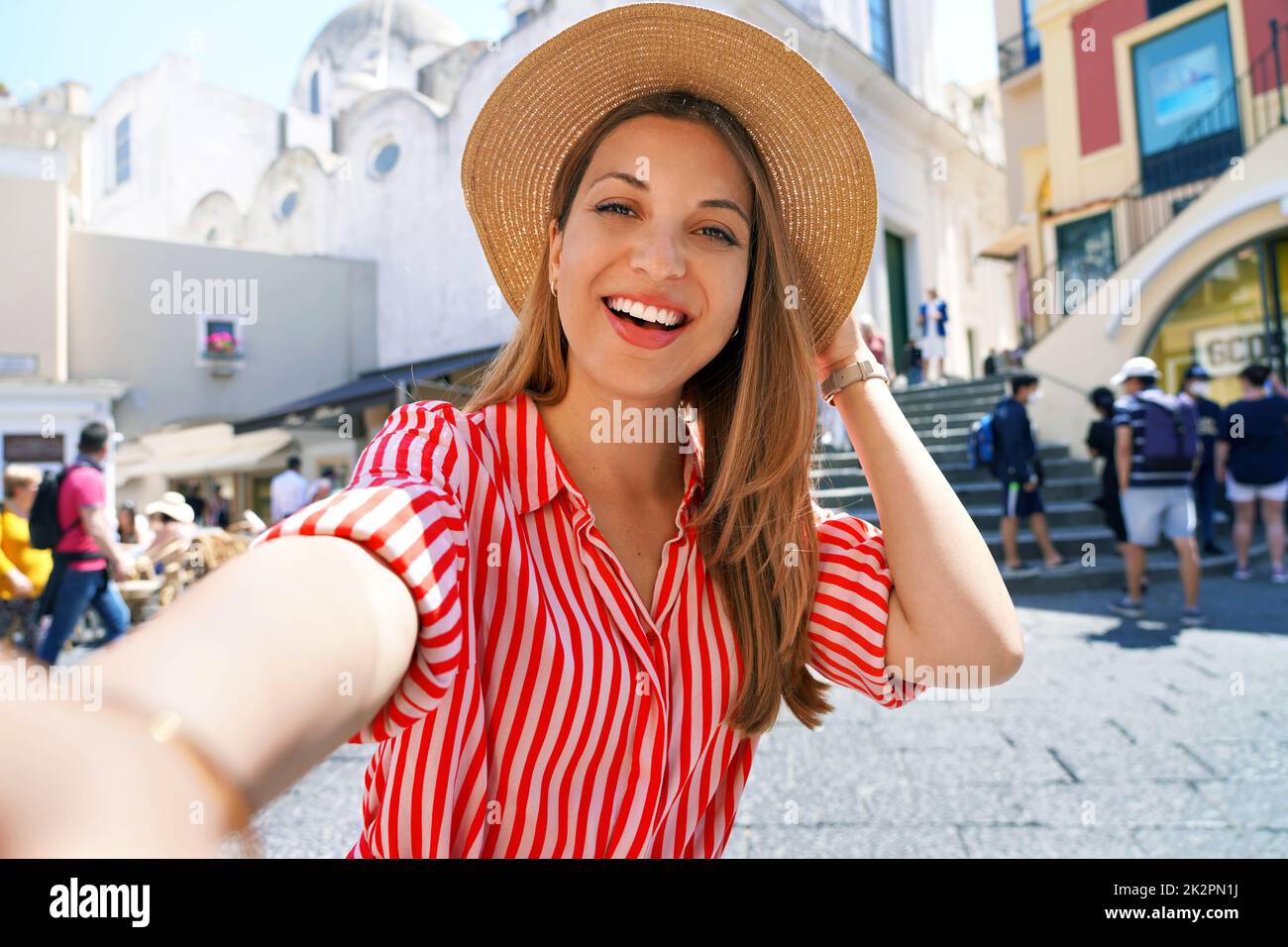 Schöne Mode-Mädchen mit gestreiftem Kleid und Hut Aufnahme Selfie-Foto in Capri Piazzetta Platz, Capri Island, Italien Stockfoto