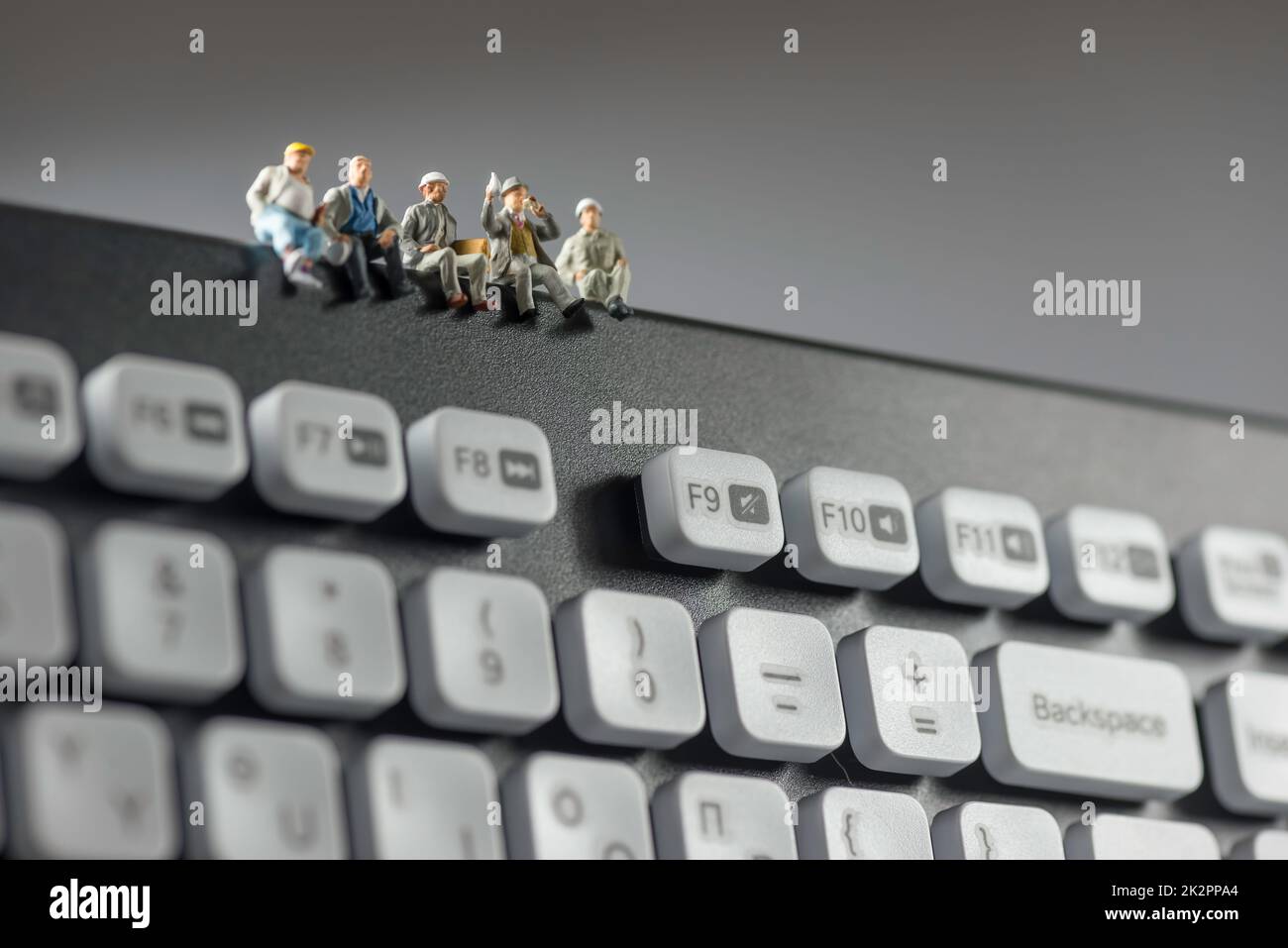 Miniaturarbeiter, die auf der Tastatur sitzen. Technologiekonzept Stockfoto