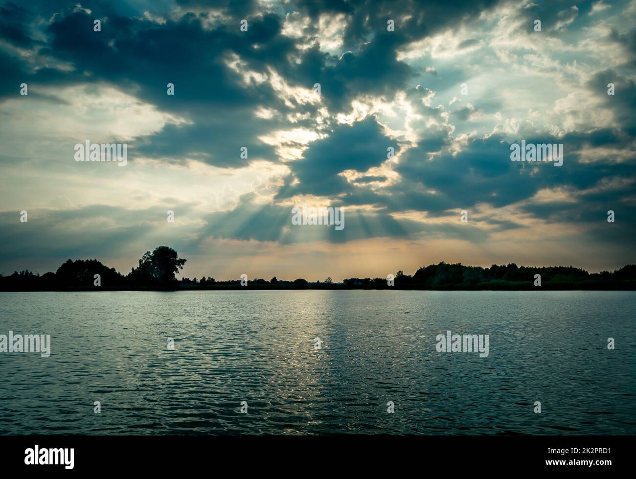 Die Sonne hinter den Wolken über dem See Stockfoto