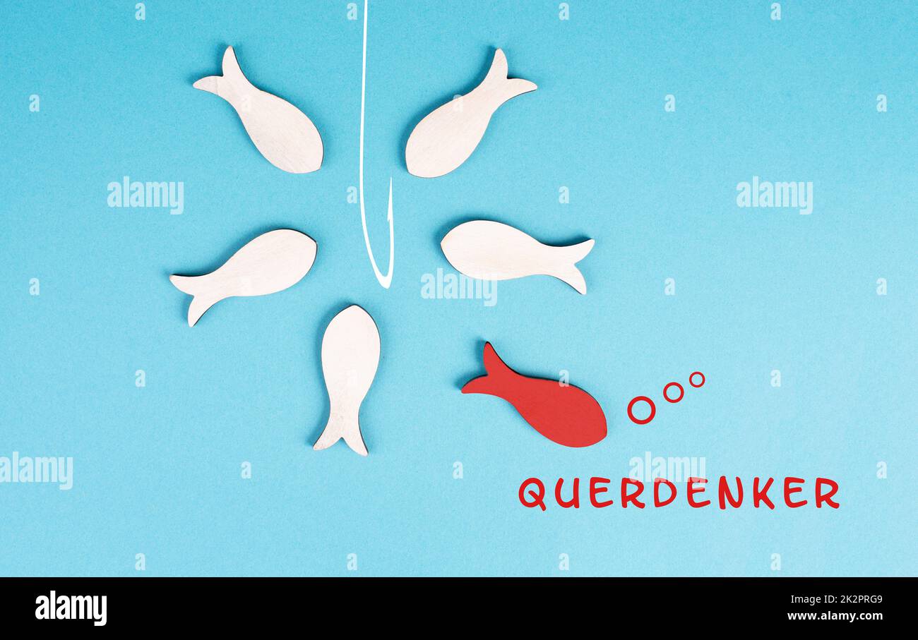 Denk mal anders, steht in deutscher Sprache auf blauem Hintergrund, roter Fisch hebt sich von der Menge ab, ist ein Nonkonformist, Verschwörungstheorie, die Gruppe schwimmt zur Angel Stockfoto