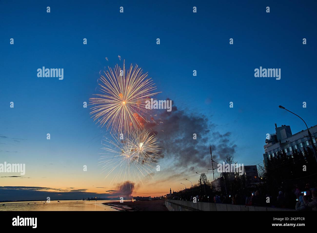 Buntes Feuerwerk auf dem Hintergrund des Himmels am Flussufer Stockfoto