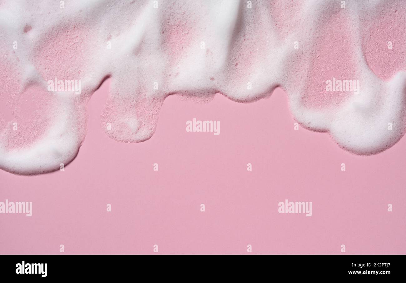 Zur Struktur des Schaumstoffes des Hautpflegereinigers. Seifenblasen mit Kopierbereich auf pinkfarbenem Hintergrund. Stockfoto