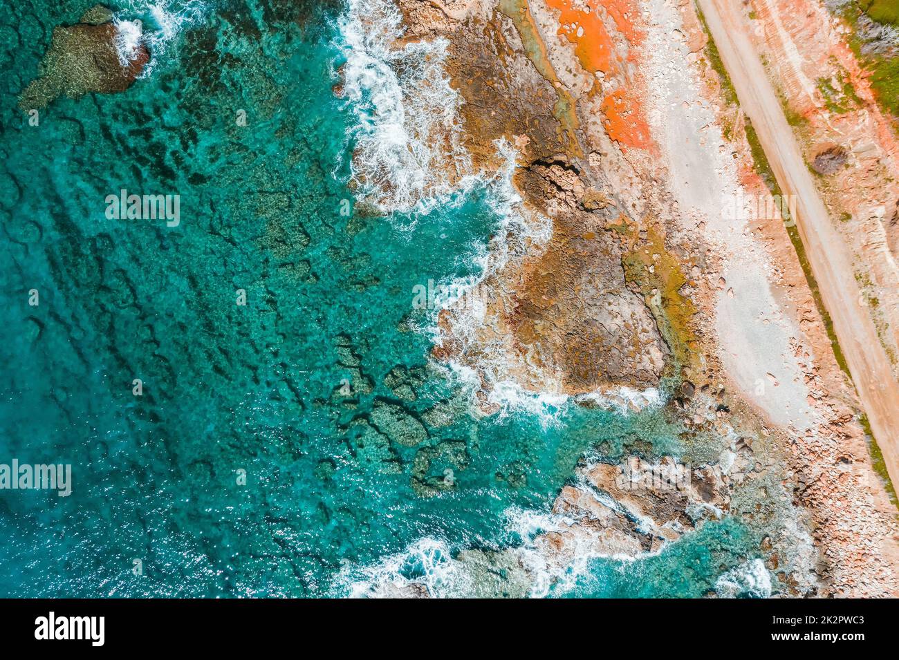 Ansicht von oben von türkisfarbenem Meer, Wellen und einer felsigen Küste Stockfoto