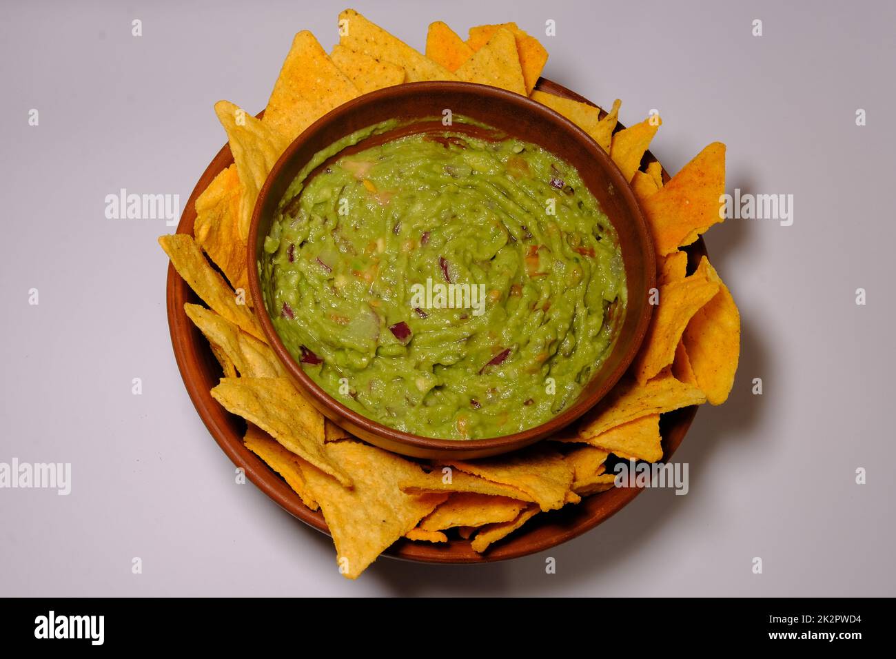 Mexikanische Guacamole-Sauce und Tortilla-Chips auf einem isolierten weißen Hintergrund. Guacamole-Schüssel mit Nachos-Chips. Draufsicht Stockfoto