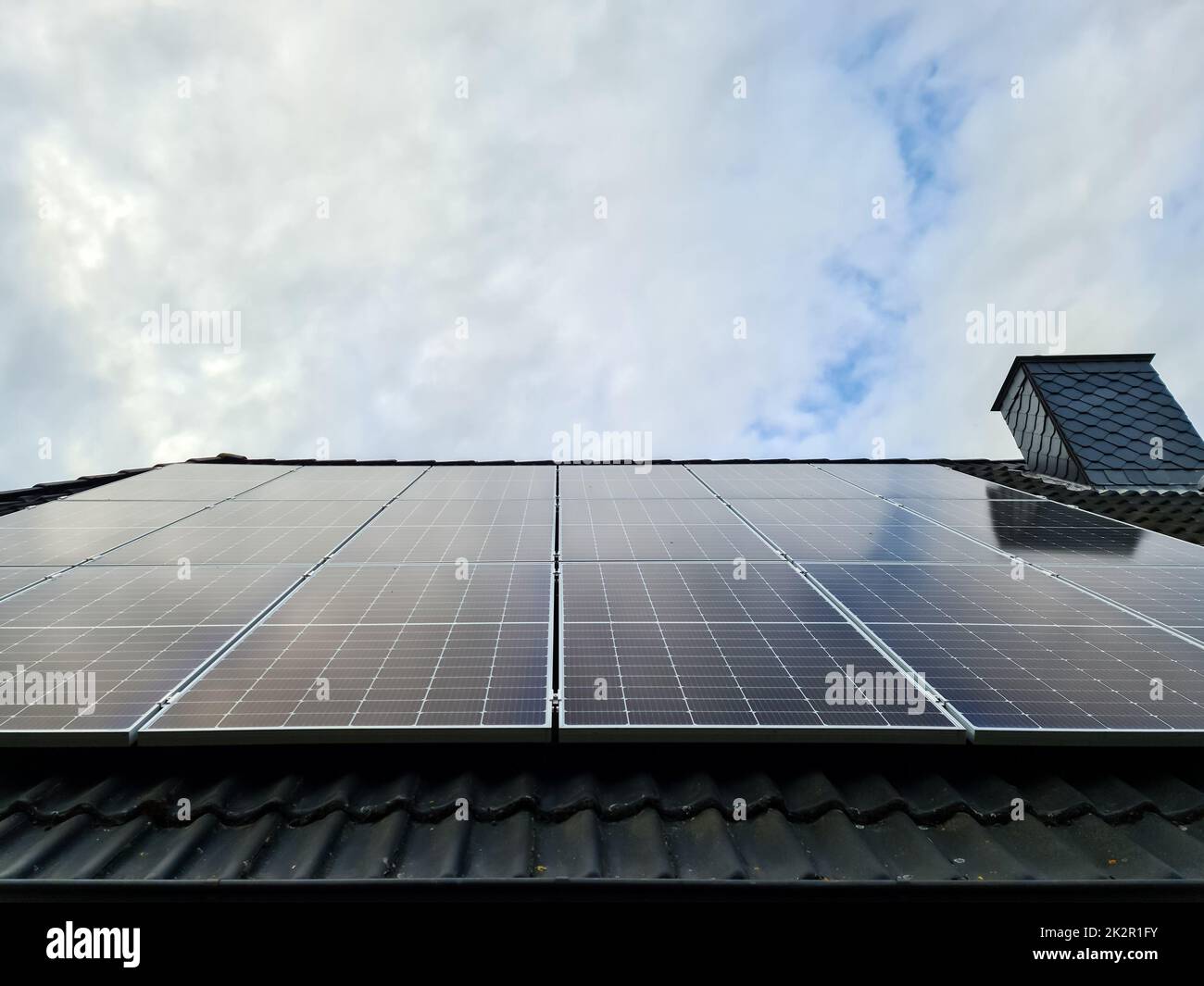 Solarmodule, die saubere Energie auf einem Dach eines Wohnhauses erzeugen Stockfoto