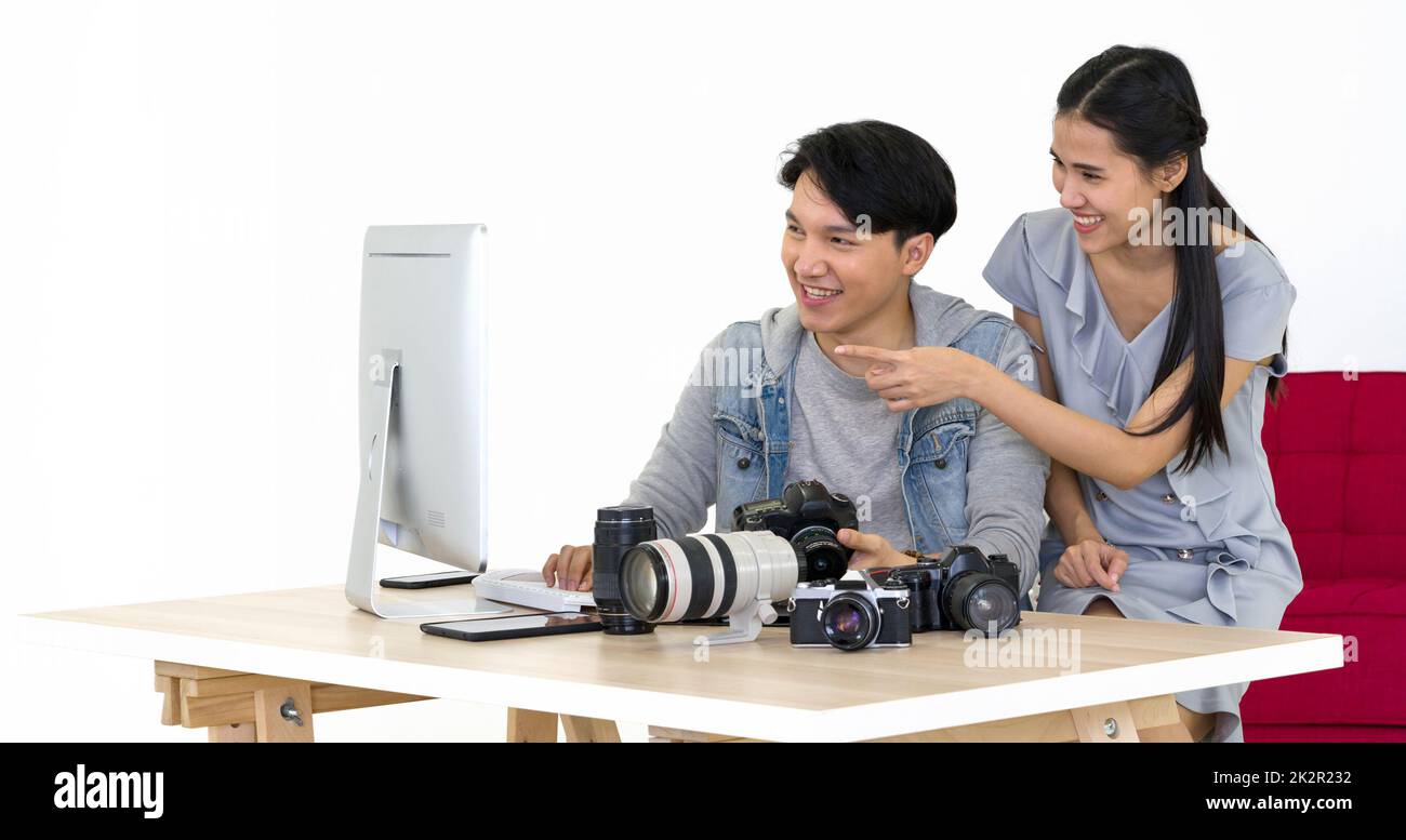 Asiatischer Fotograf und Modell, der sich Bilder ansieht, die auf dem Computermonitor aufgenommen wurden. Das junge Model ist sehr zufrieden mit ihrem Foto. Die Atmosphäre im Fotostudio. Stockfoto