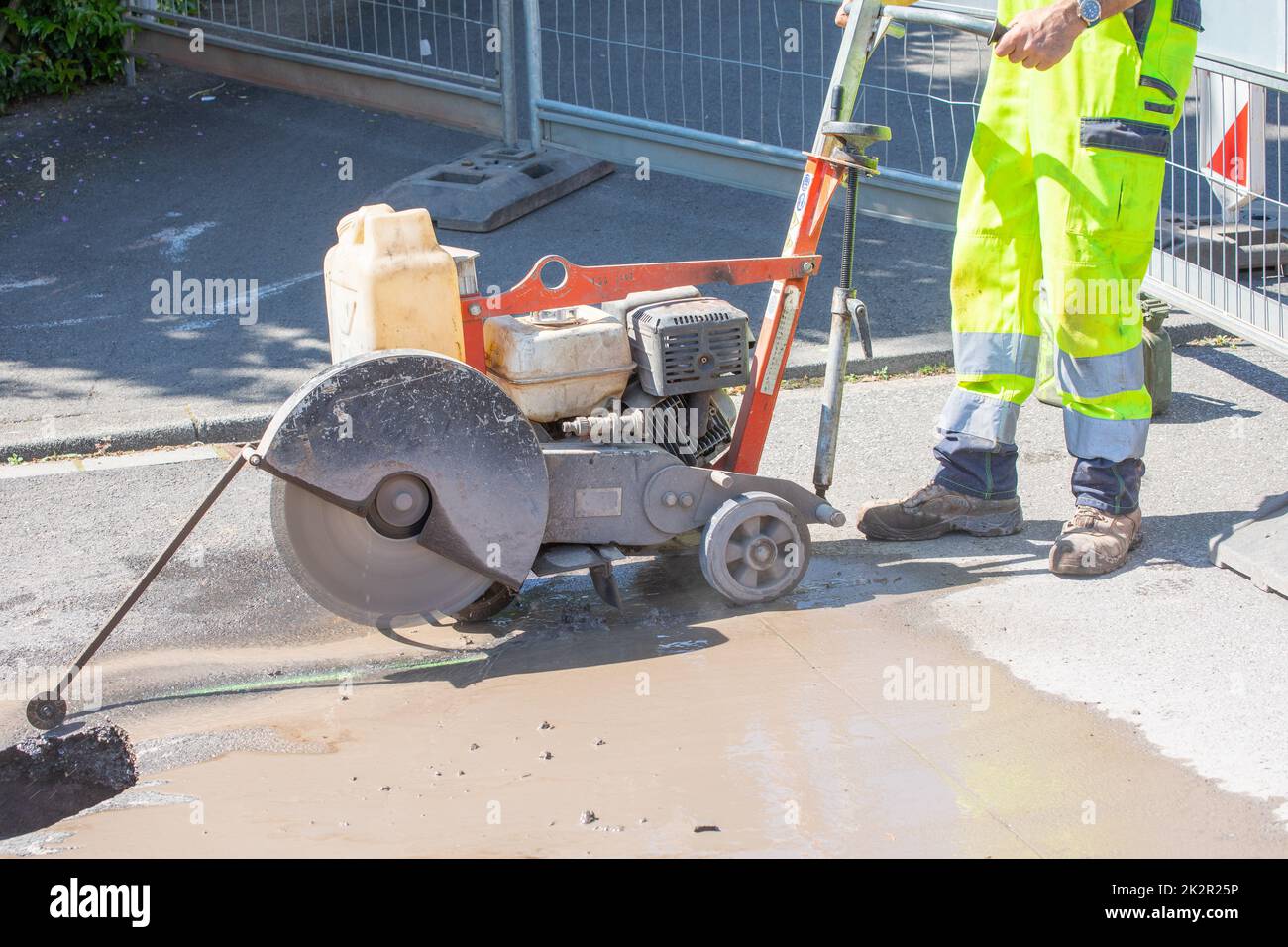 Straßenarbeiter schneidet Beton mit einer Betonschneidemaschine Stockfoto