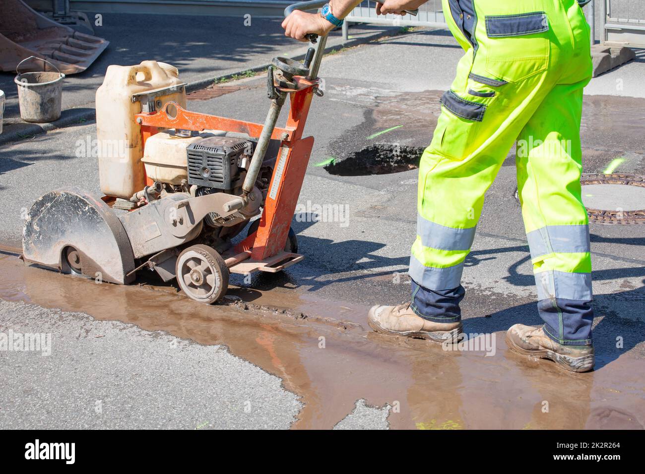 Straßenarbeiter schneidet Beton mit einer Betonschneidemaschine Stockfoto