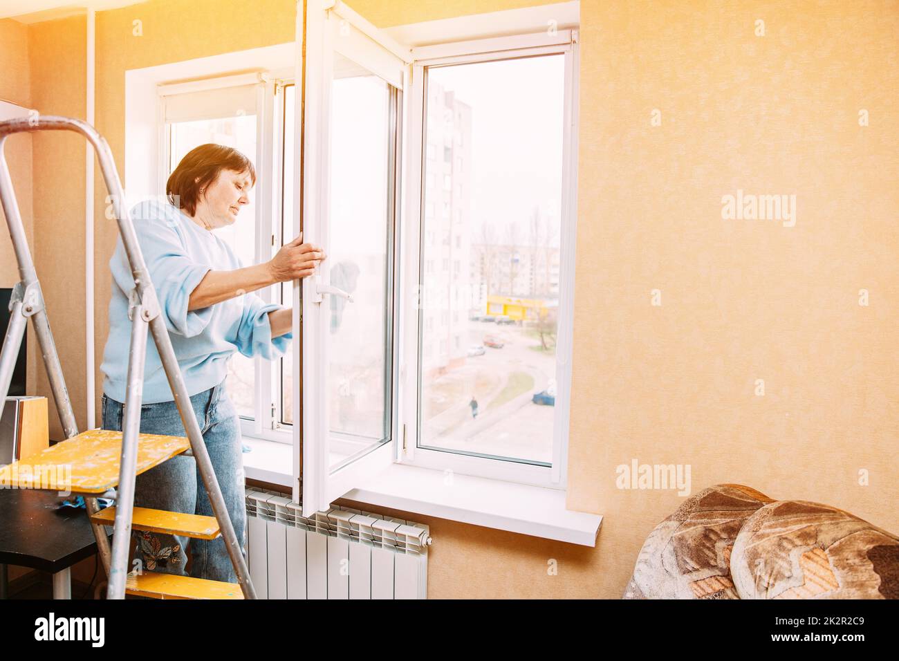 Glücklich Schüchtern Reifen Frau Reinigung Fenster. Kaukasische Frau Im Mittleren Alter. Konzept Für Aktive Senioren. Ältere Frau Reinigung Apartment. Hausfrau Stockfoto
