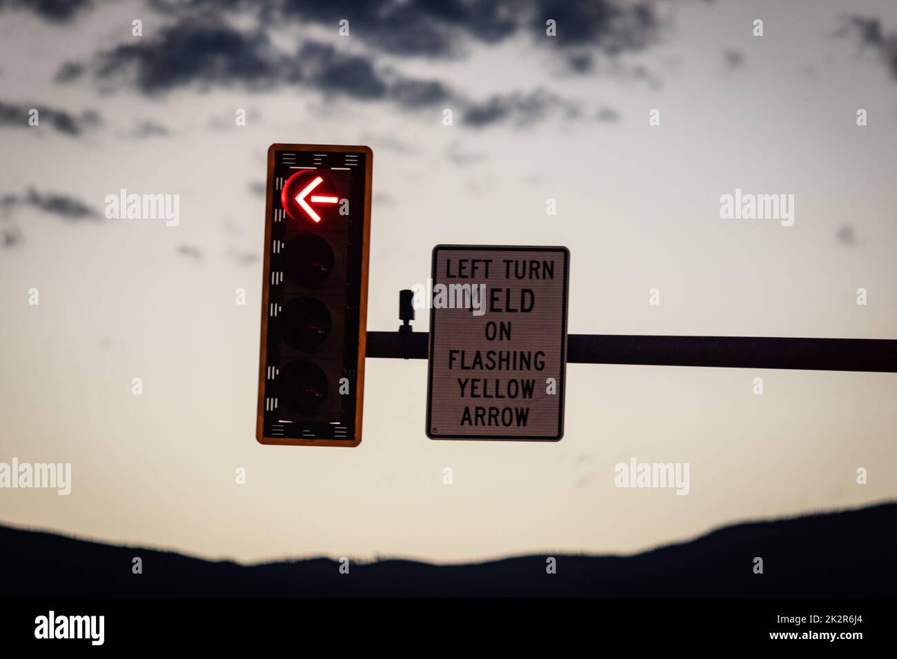 Nahaufnahme einer Ampel und eines Schilds mit der Aufschrift „Left Turn Yield on blinking yellow arrow“ Stockfoto