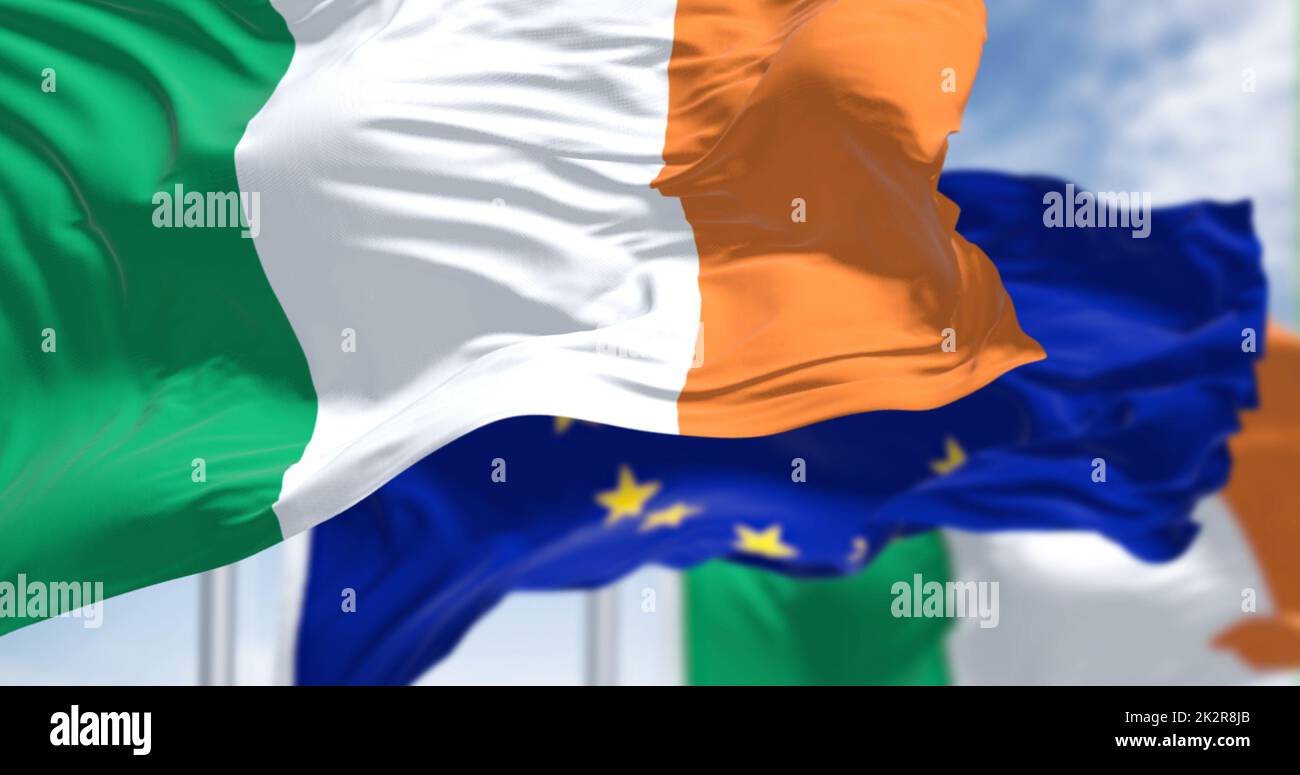 Detail der im Wind winkenden Nationalflagge Irlands mit verschwommener Flagge der europäischen Union Stockfoto