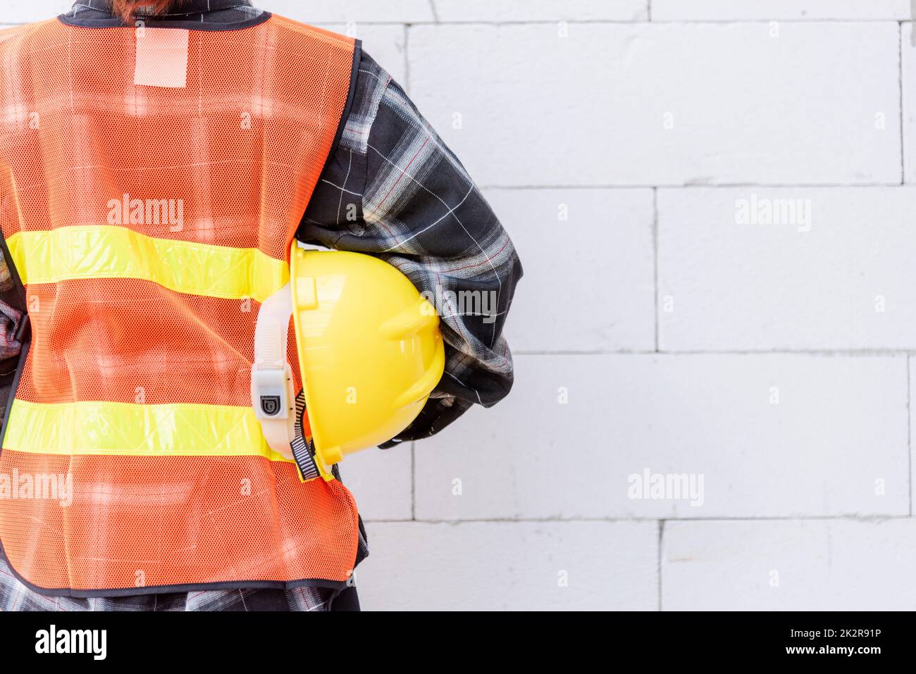 Rückansicht des Technikers, Architekten, Vorgesetzten tragen reflektierende Kleidung zur Sicherheit der Arbeit Halten Sie den Schutzhelm Stockfoto