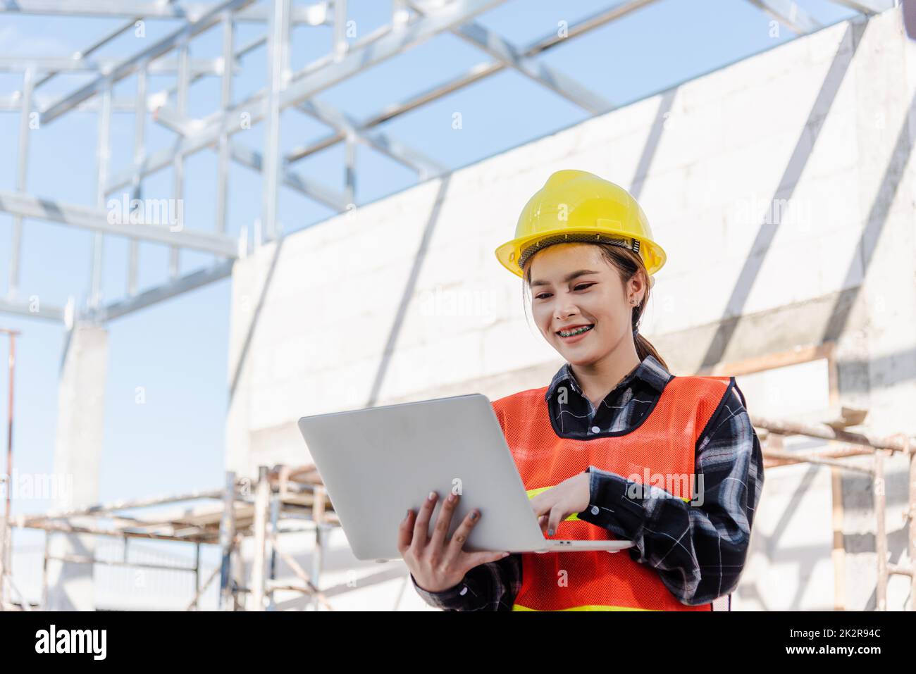 Asiatische Architektenfrau mit Laptop inspiziert und überwacht den Fortschritt der Infrastruktur auf der Baustelle Stockfoto
