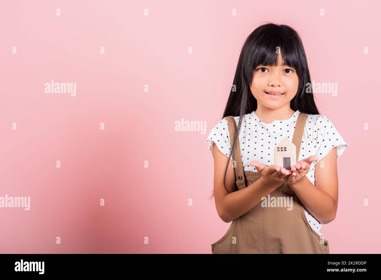 Asiatisches kleines Kind, 10 Jahre alt, hält ein Holzhaus-Model an den Händen Stockfoto