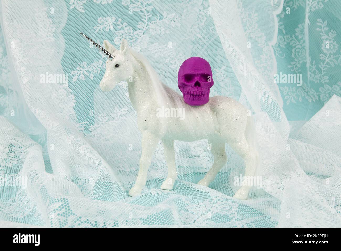 Ein glänzendes weißes Einhorn mit einem Plastikschädel auf dem Rücken Stockfoto