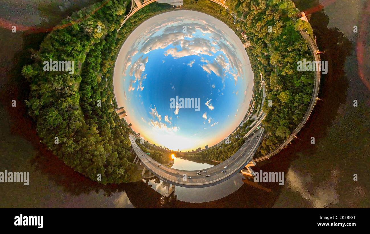 Ein wunderschöner bewölkter Himmel an einem sonnigen Tag, abgerundet, um wie ein Erdball mit einer Straße über einen Fluss auszusehen - 360 Grad Luftaufnahme Stockfoto