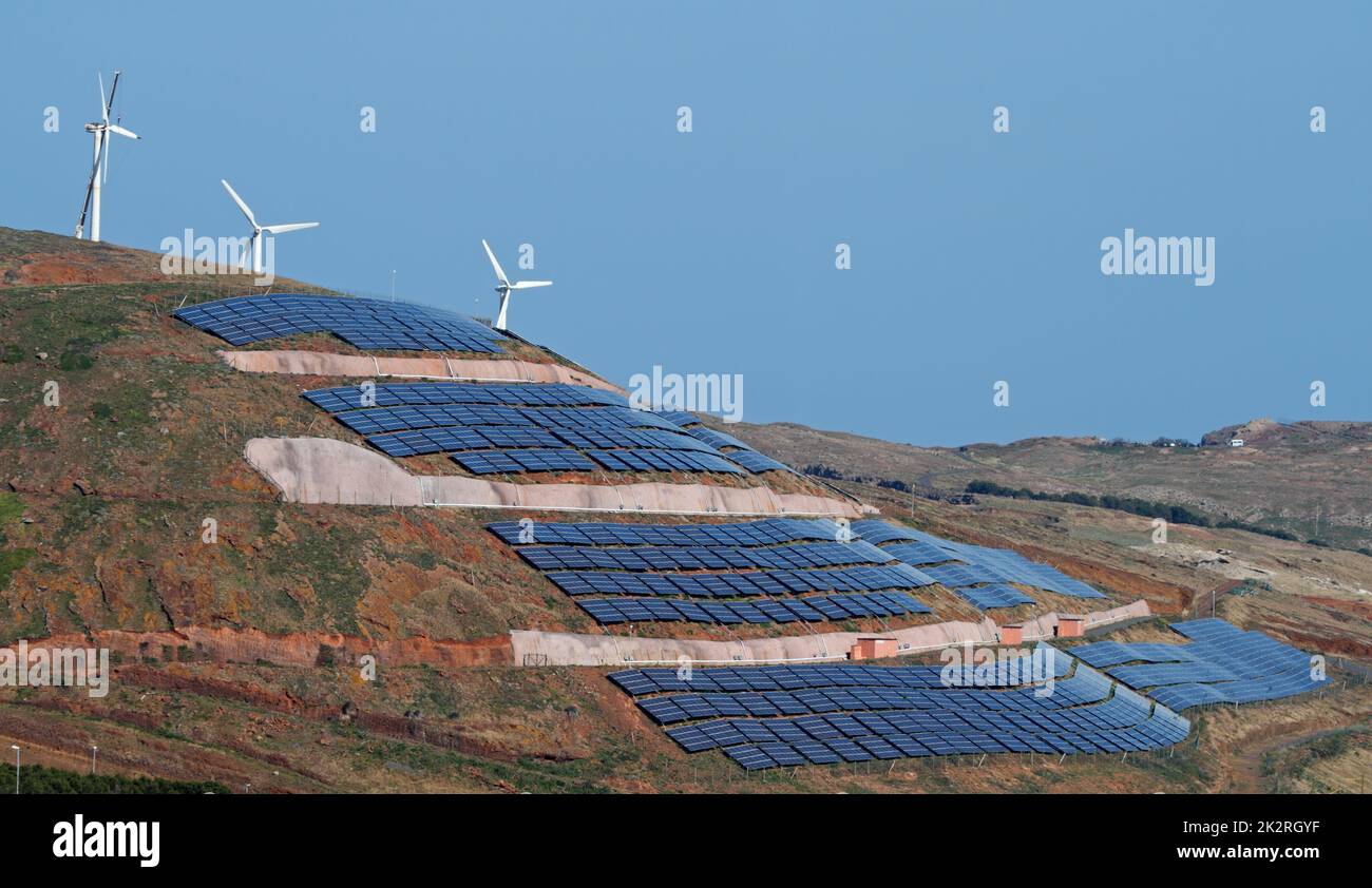 Photovoltaik-Sonnenkollektoren und Windturbinen, die Strom auf einem Hügel und blauem Himmel erzeugen. Ökologie grün Natur Konzept. Stockfoto