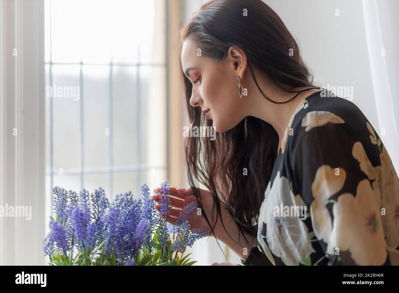 Seitenansicht Porträt von attraktiven dunkelhaarigen Mädchen Biegen über lila Blüten horizontal. Stockfoto