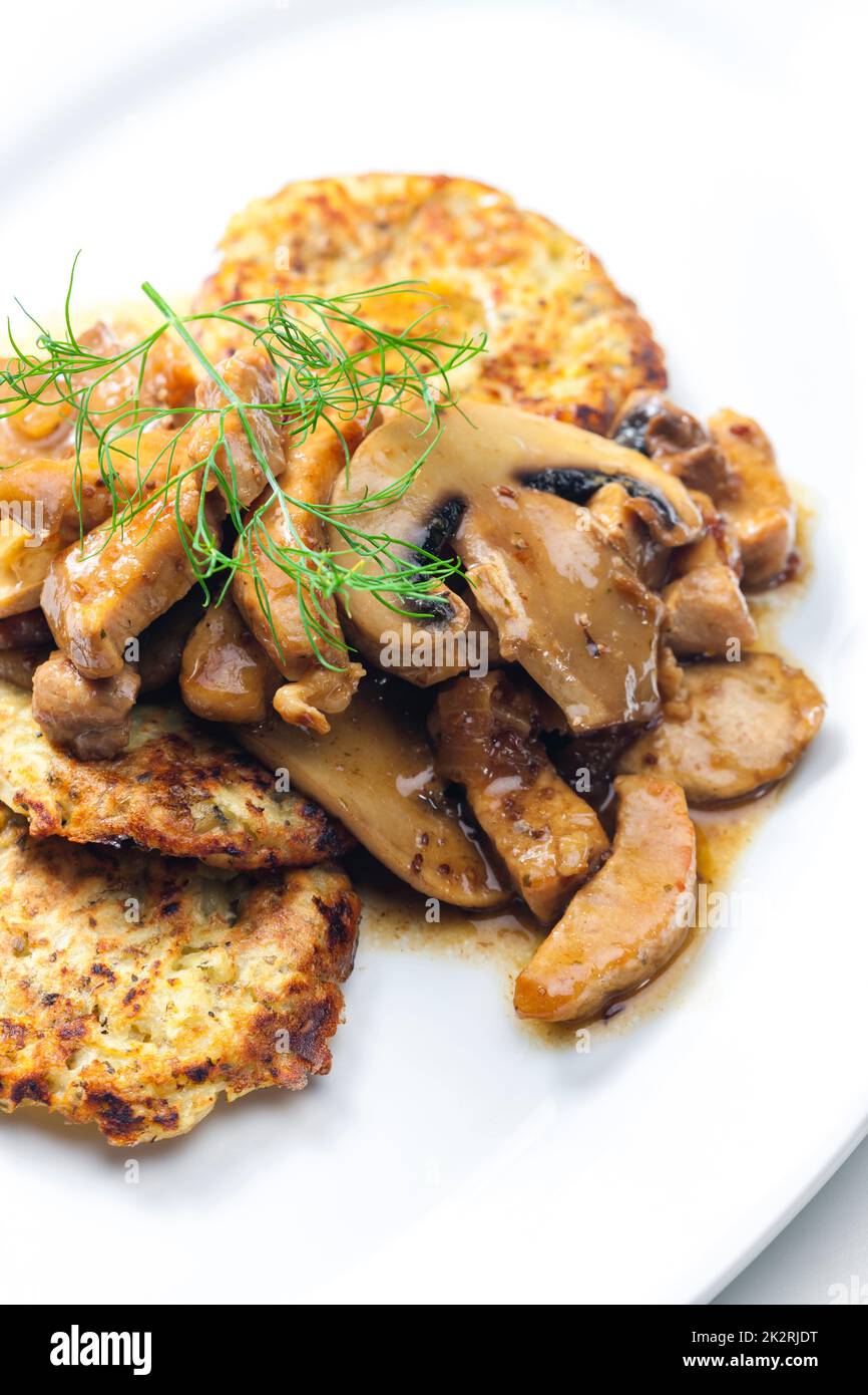 Hühnerfleisch mit Pilzsauce serviert mit Kartoffelkuchen Stockfoto