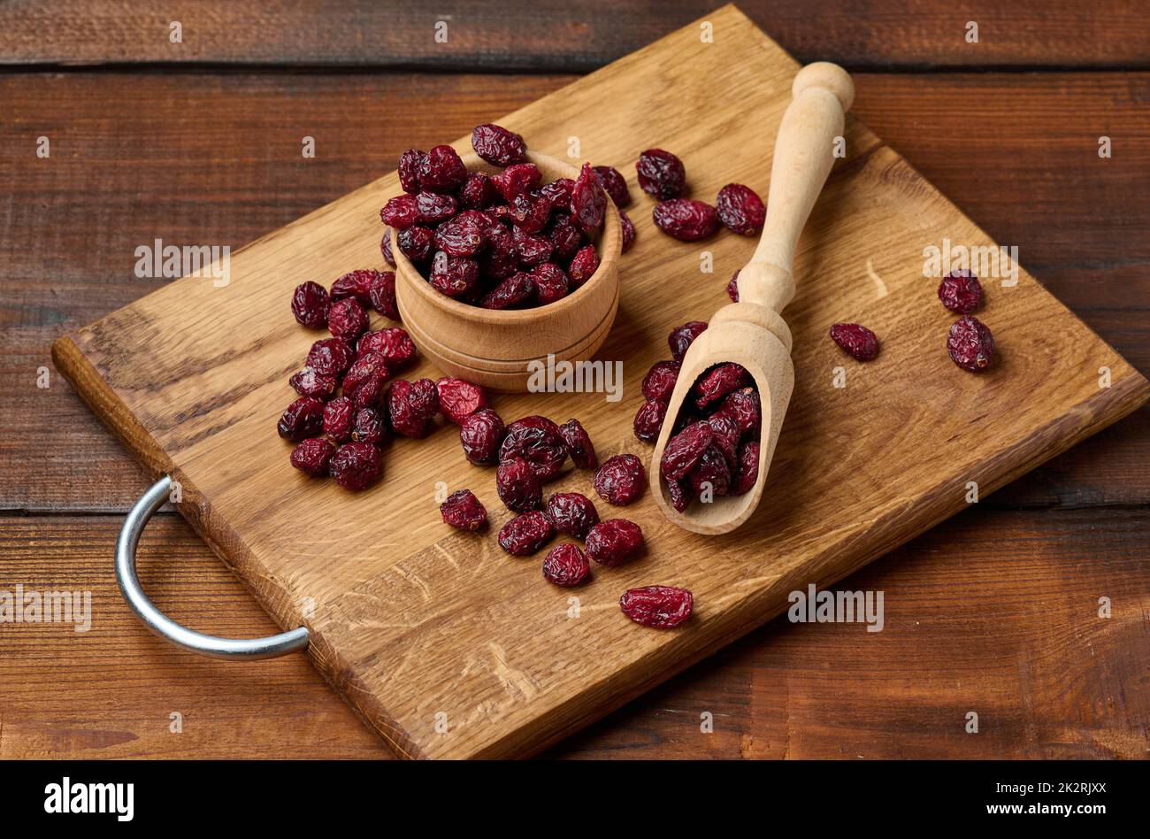 Ein paar getrocknete Preiselbeeren in einem Holzlöffel auf einem braunen Tisch. Köstliche Beeren, Blick von oben Stockfoto