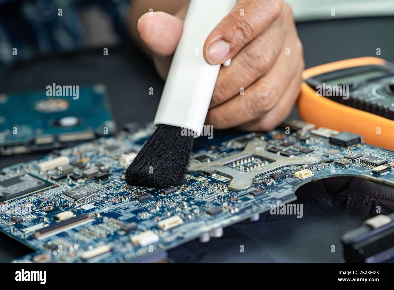 Der Techniker verwendet eine Bürste und eine Luftgebläse, um Staub im Leiterplattencomputer zu reinigen. Reparatur Upgrade und Wartung Technologie. Stockfoto