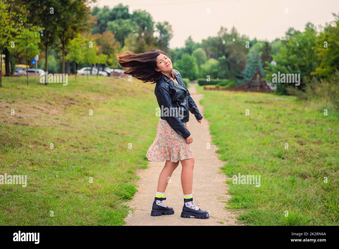 Schöne junge lächelnde Frau dreht ihren Kopf mit langen schwarzen Haaren in der Natur Stockfoto
