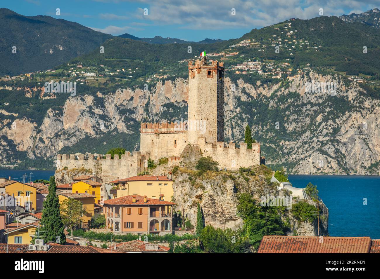 Idyllischer Gardasee oberhalb der Altstadt von Malcesine mit italienischer Flagge und Bergkette Stockfoto