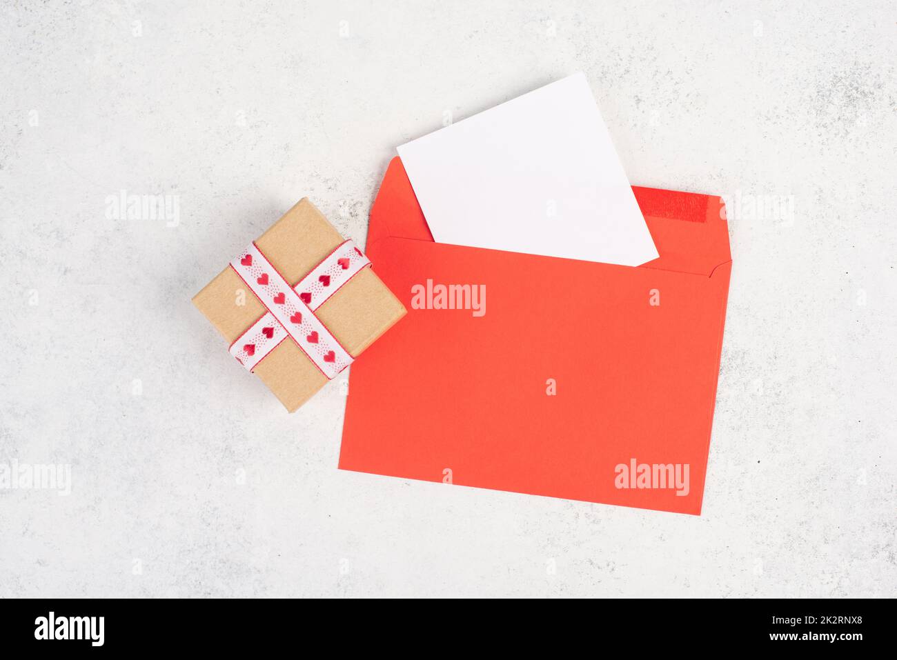 Roter Umschlag mit leerem Papier, Geschenkbox mit Herzen, texturiertem Hintergrund, Geburtstag, Muttertag, Vatertag und valintines-Grußkarte Stockfoto