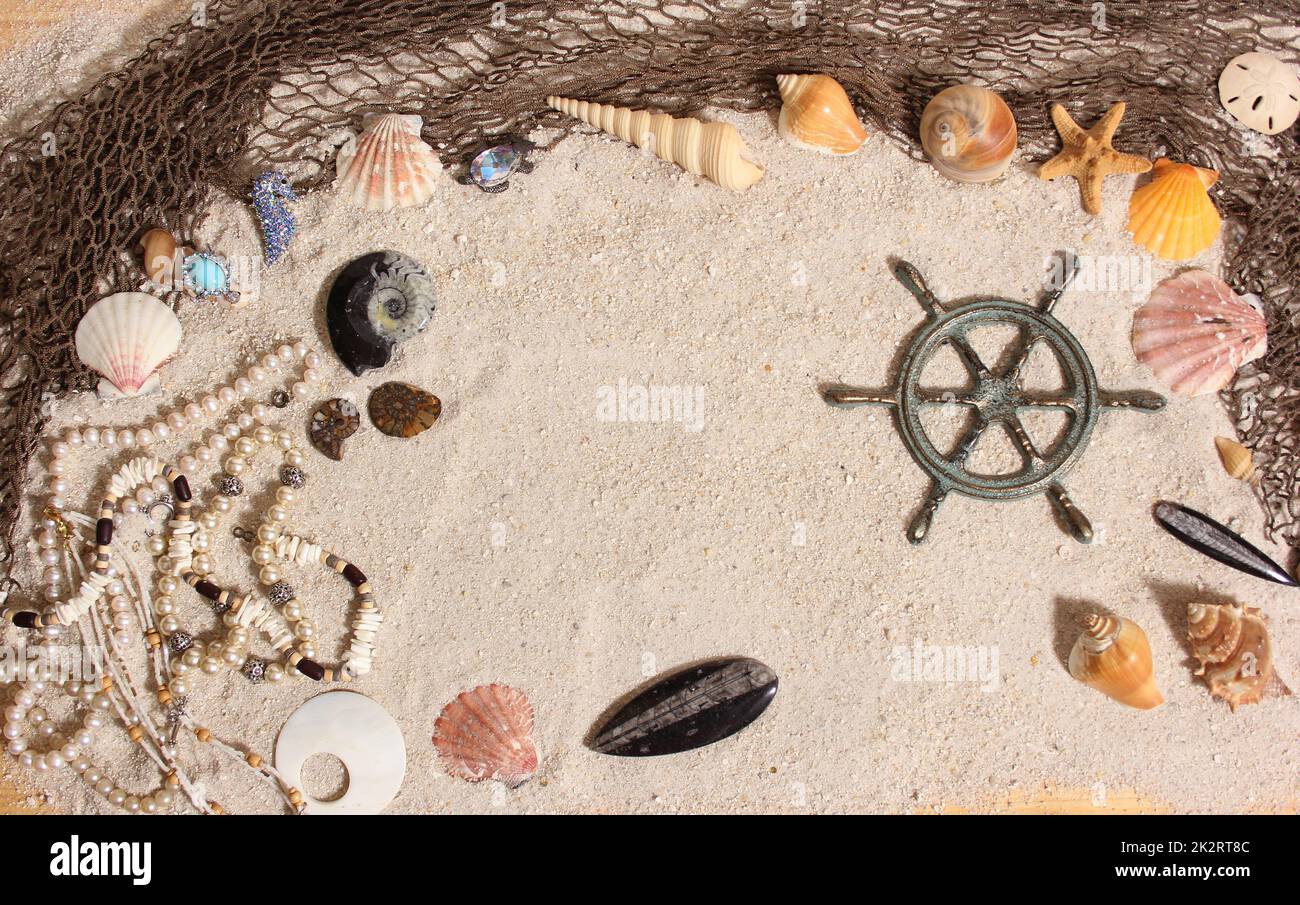 Kapitänsrad mit Fischernetz und Meeresmuscheln im maritimen Sand-Hintergrund Stockfoto
