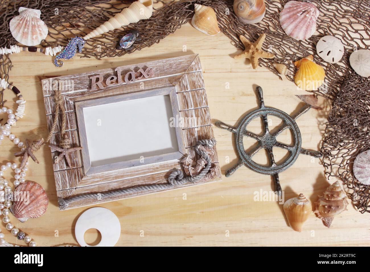 Leerer Rahmen auf Holzhintergrund mit Meeresmuscheln und Fischernetz. Nautisches und Küstenthema Stockfoto