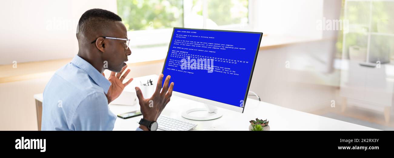Besorgter Mann Am Computer Mit Systemausfall Auf Dem Bildschirm Stockfoto