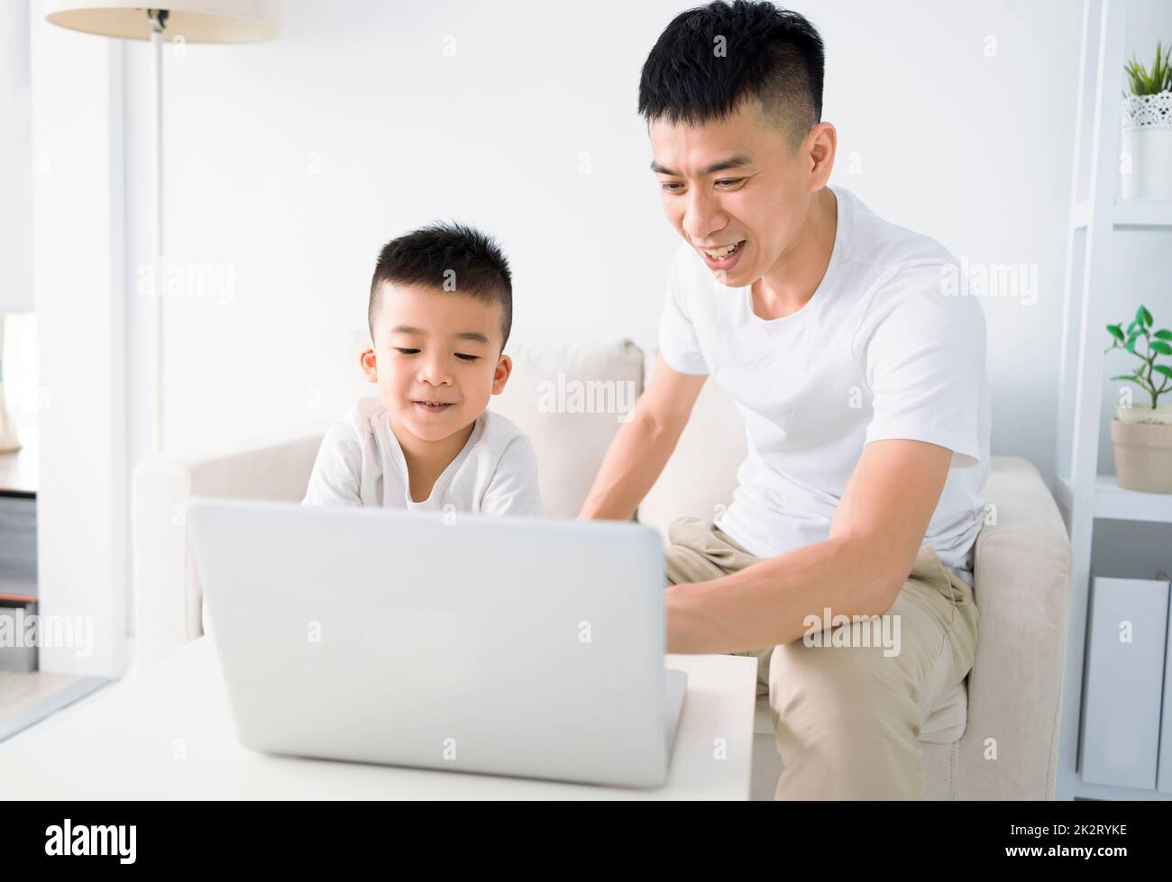 Online-Kindererziehung. Vater helfen Sohn bei der Hausarbeit. Junge in Videokonferenz mit Lehrer auf Laptop zu Hause. Stockfoto
