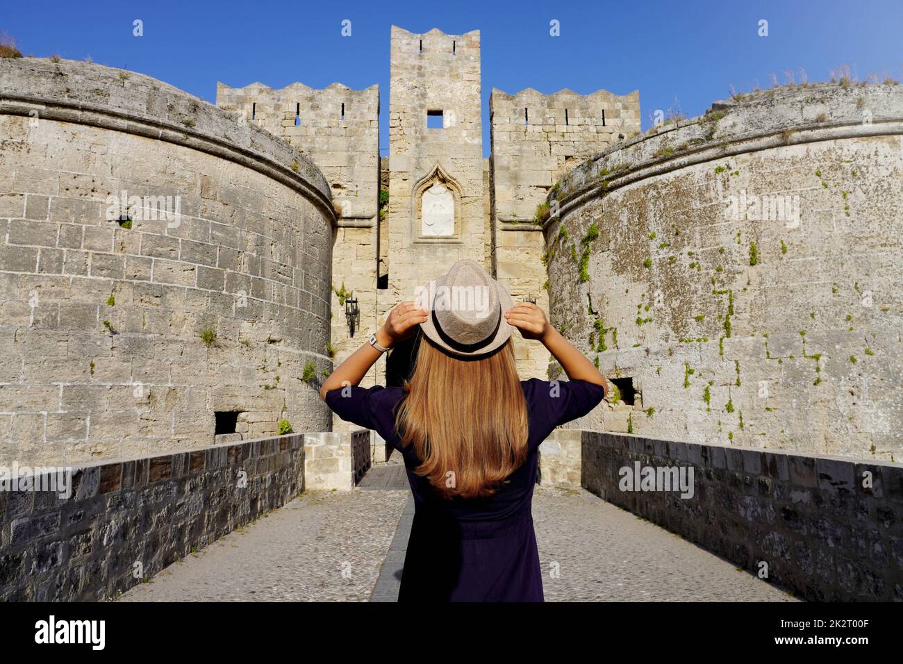Tourismus in Griechenland. Rückansicht eines Touristen-Mädchens, das die alten Befestigungsanlagen von Rhodos-Stadt, Griechenland, besucht. UNESCO-Weltkulturerbe. Stockfoto