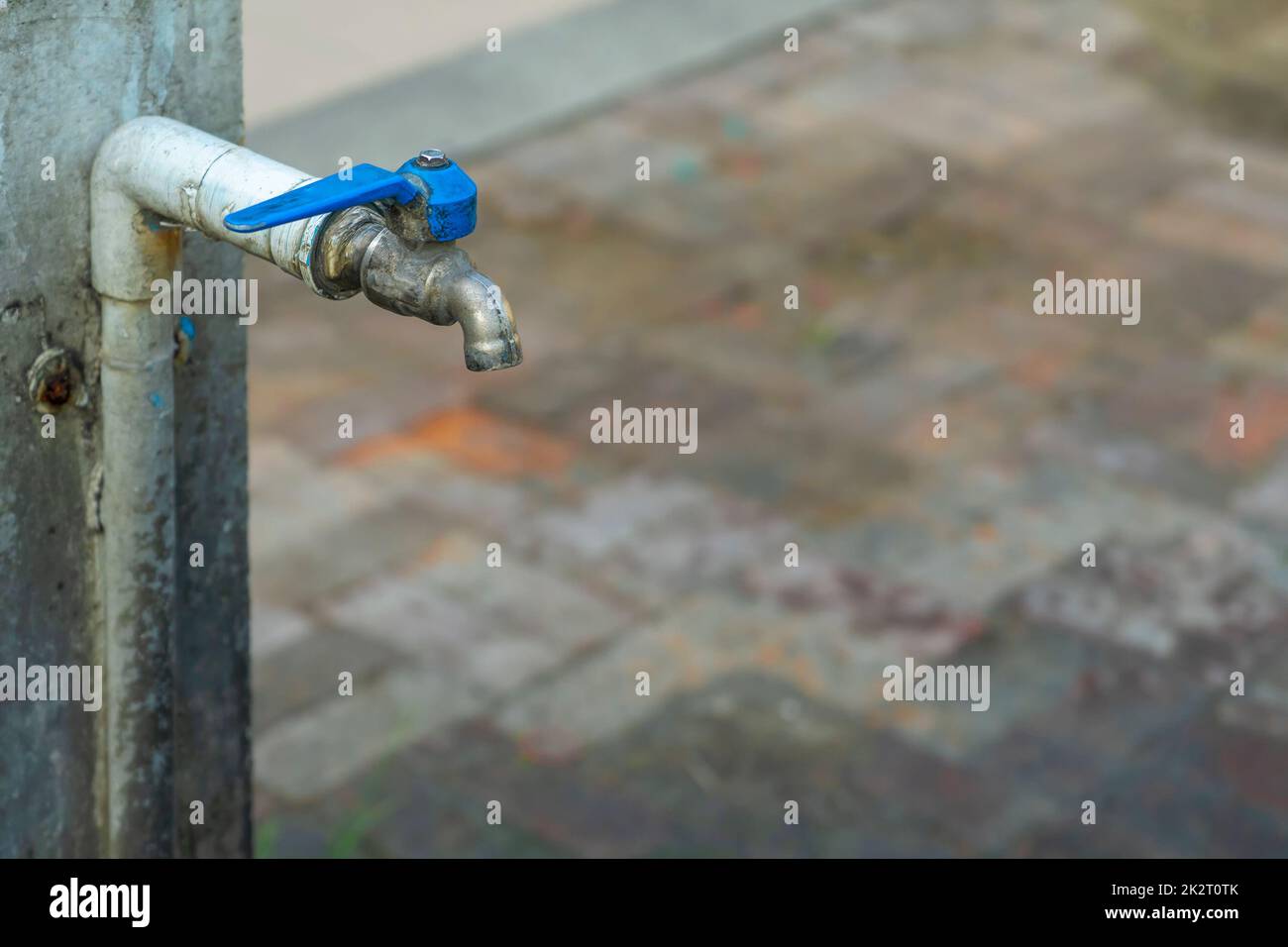 Alter Ventilhahn mit blauem Leitungswasser. Stockfoto