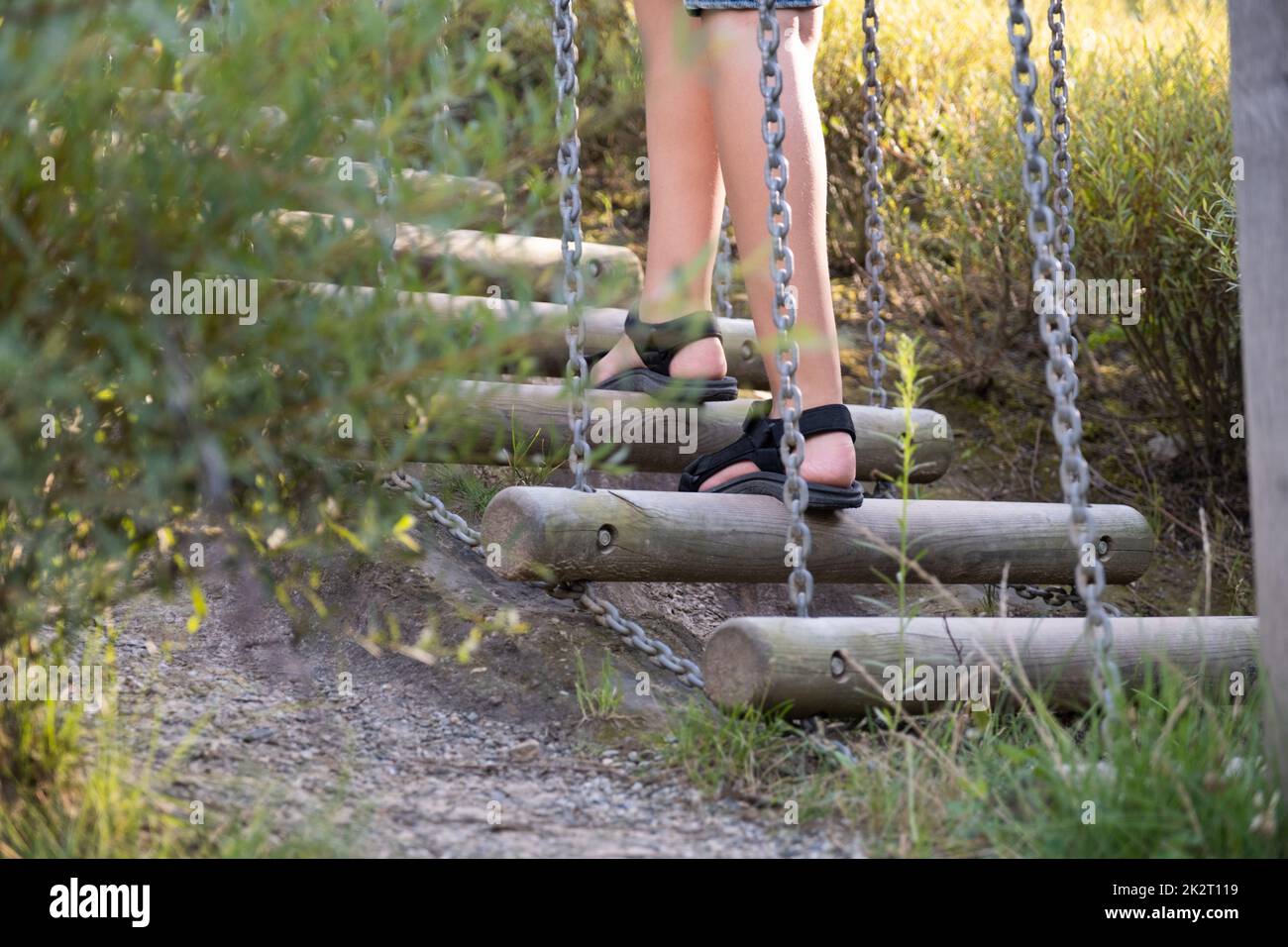 Das junge kaukasische Kind spielt auf dem Spielplatz und klettert im Seilpark auf eine Holzleiter. Stockfoto