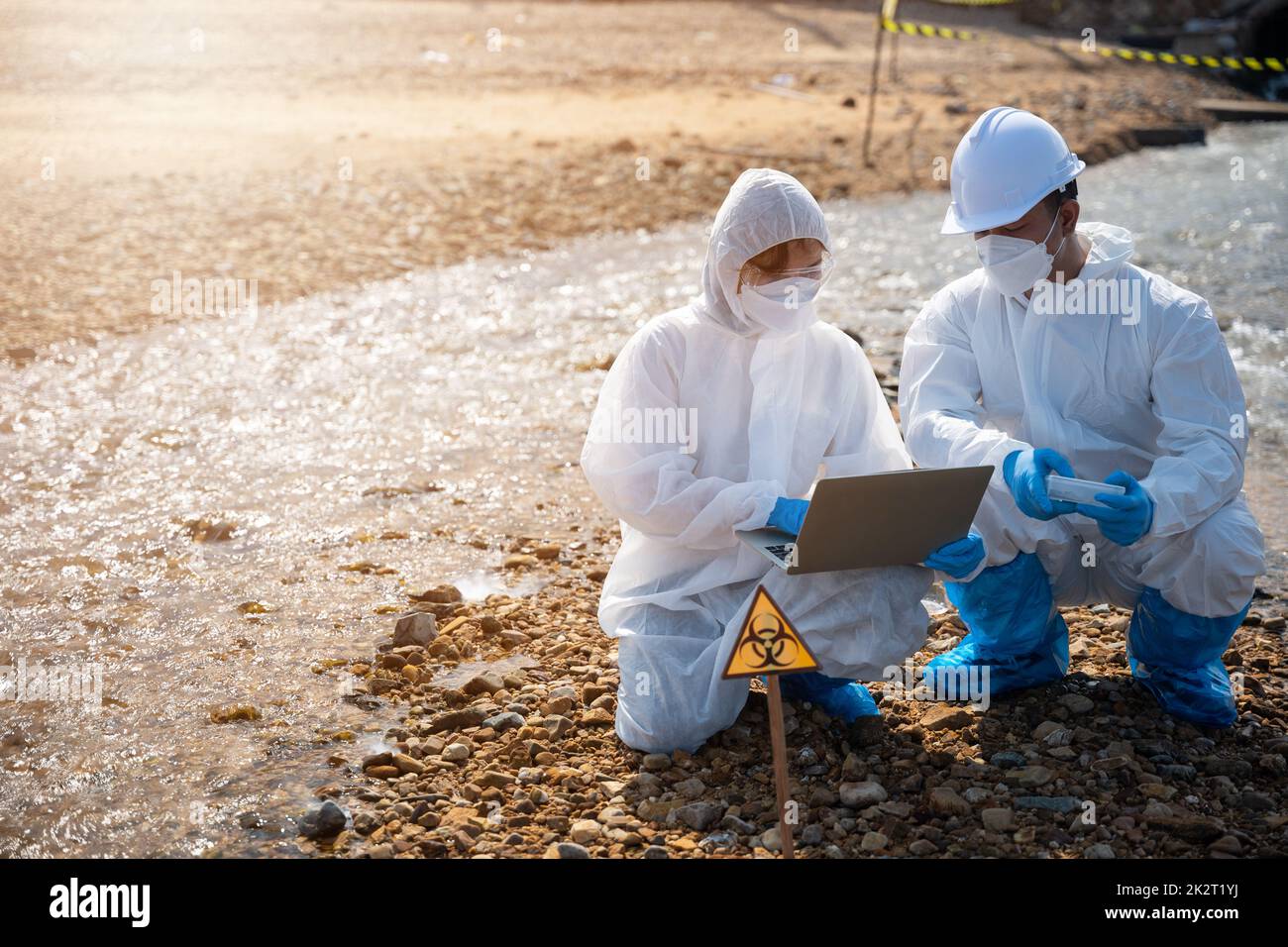Biologe tragen Schutzanzug und Maske sammelt Abwasserproben aus der Industrie Stockfoto