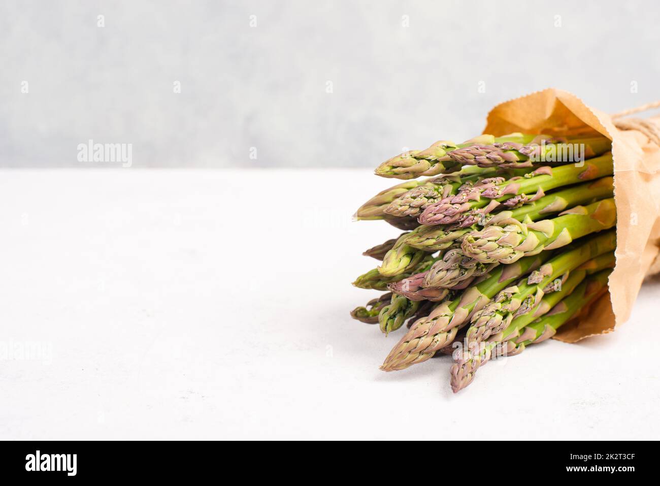 Frisches grünes Spargelbündel auf einem weiß strukturierten Tisch, Gemüse im Frühjahr, Gourmet-Küche, Kochen einer veganen Mahlzeit Stockfoto