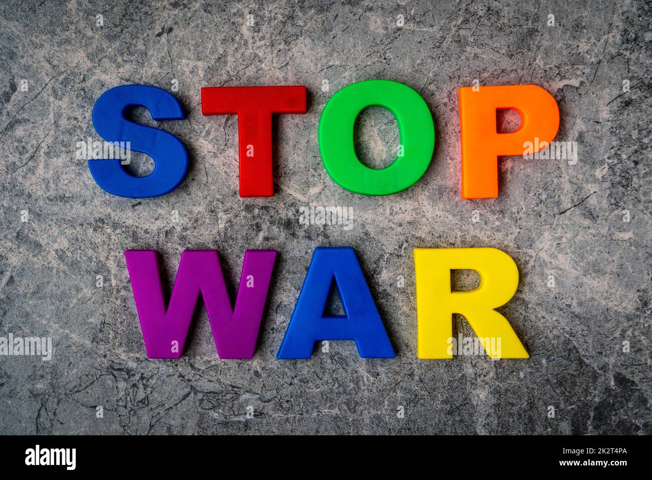 Die Inschrift Stop war in Plastikbuchstaben auf einem Steinhintergrund Stockfoto