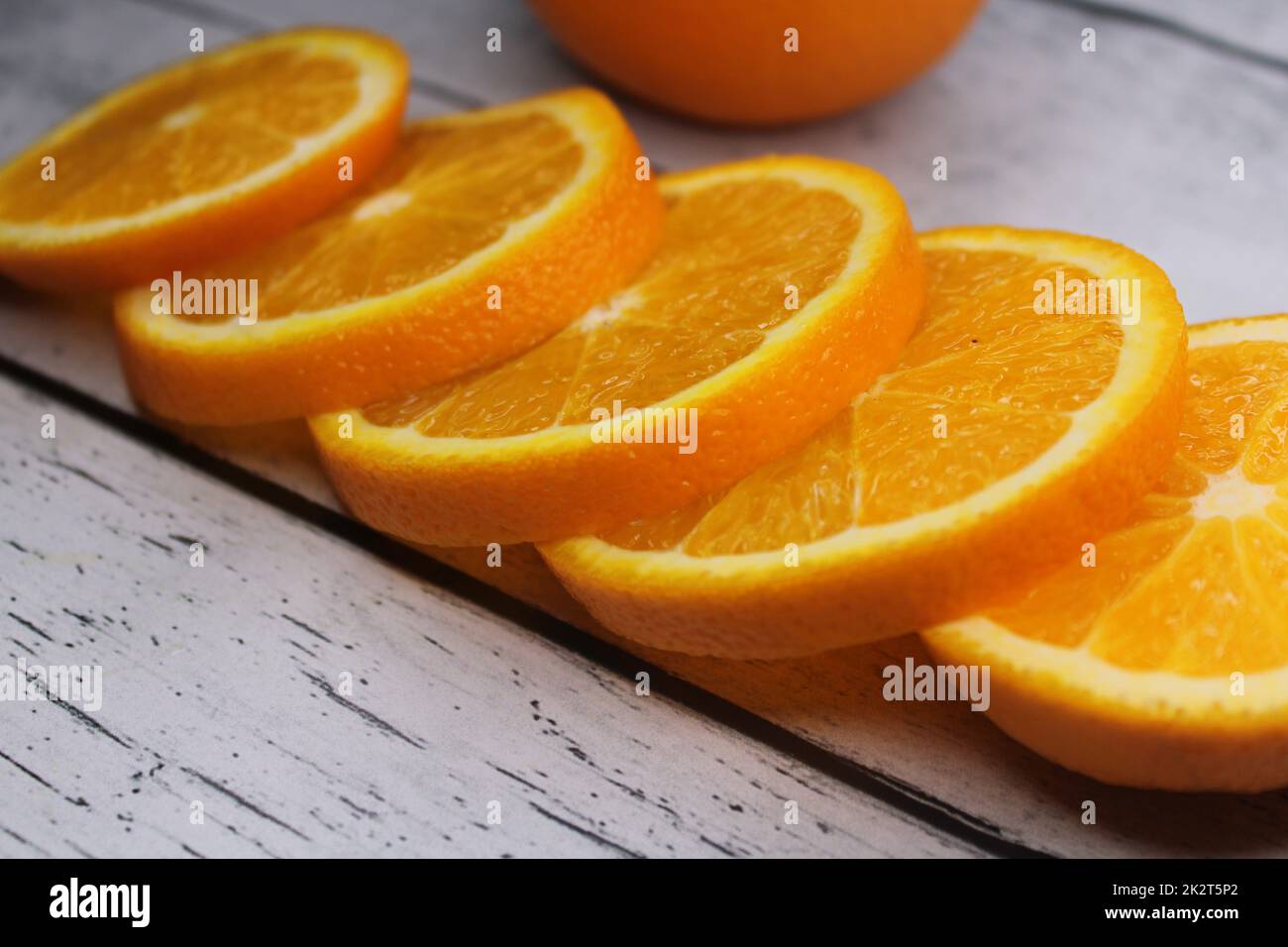 Orangefarbene Scheiben, die auf einem Holztisch übereinander gestapelt sind. Stockfoto