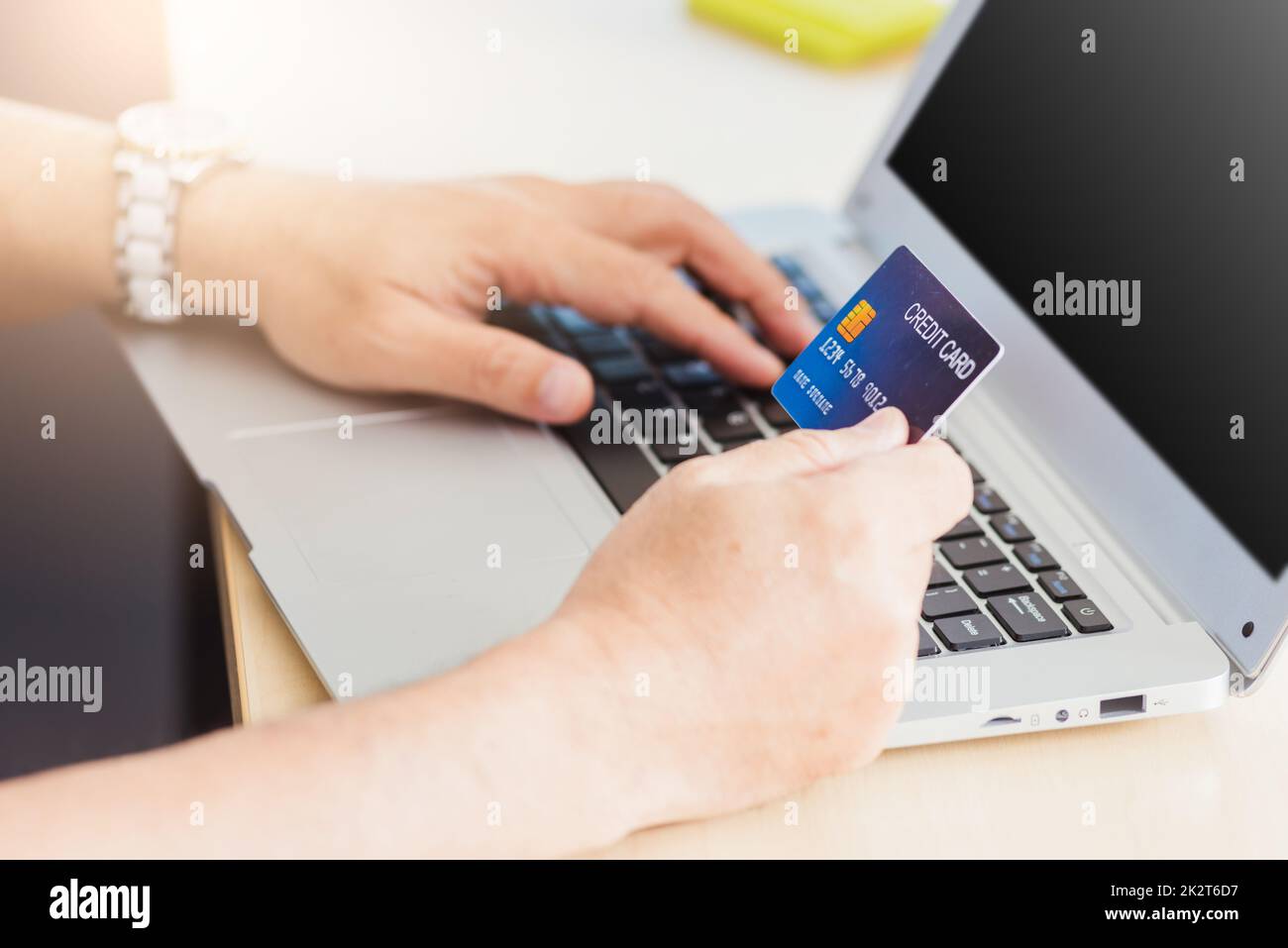 Älterer Erwachsener, der eine Kreditkarte hält und Technologie auf einem Laptop nutzt Stockfoto