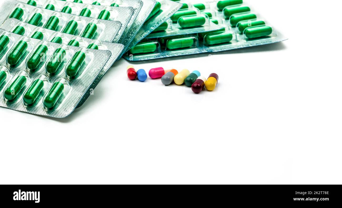 Grüne Antibiotikakapsel in Blisterpackung und mehrfarbige Kapseltablette auf weißem Hintergrund. Antibiotikaresistenz und verschreibungspflichtiges Arzneimittelkonzept. Pharmazeutische Produkte. Pharmazeutische Industrie. Stockfoto