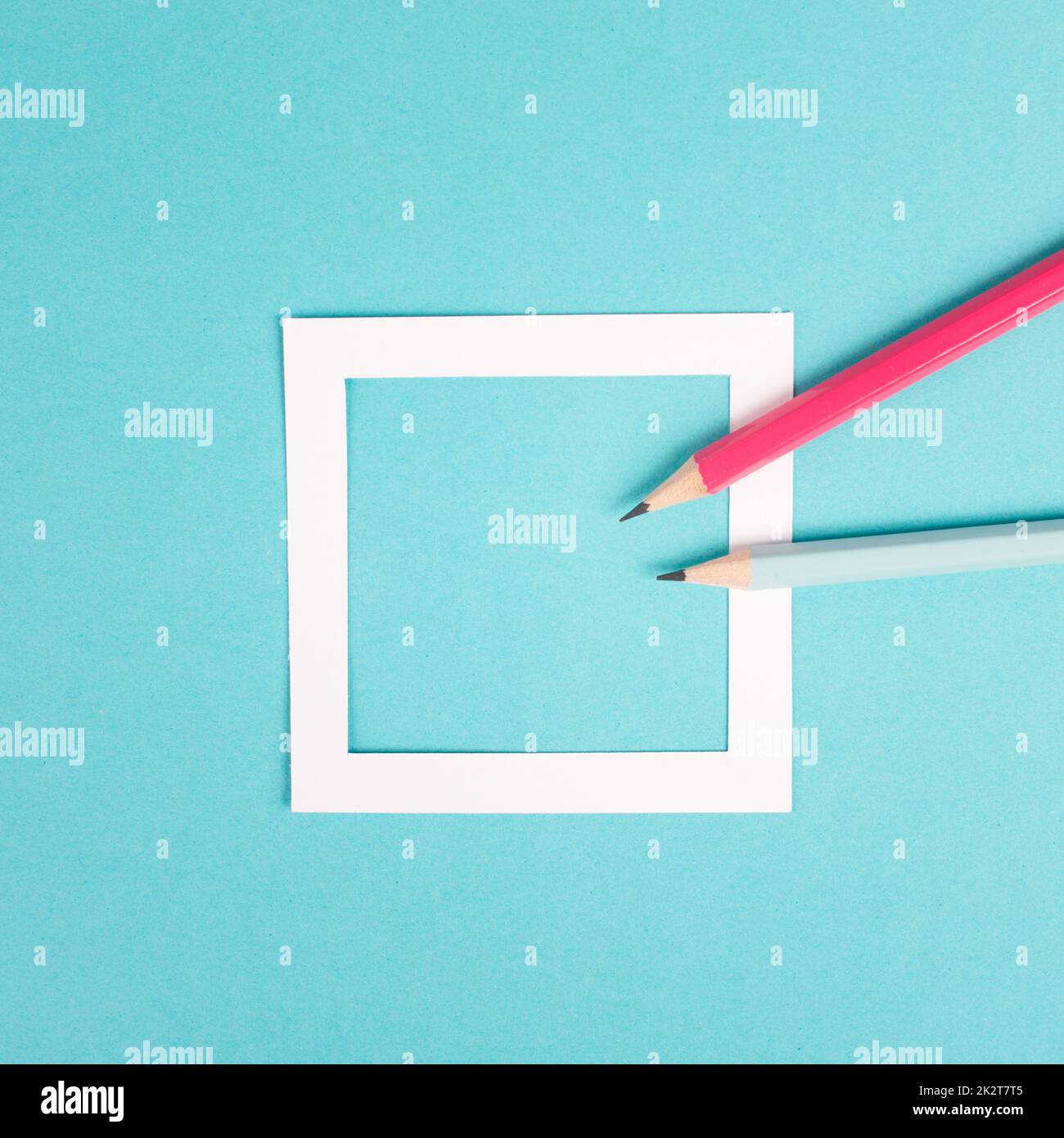 Bleistifte auf blauem Papierhintergrund, weißer Rahmen mit Platz für Text, Minimalismus, kreatives und geschäftliches Konzept, pastellfarben Stockfoto