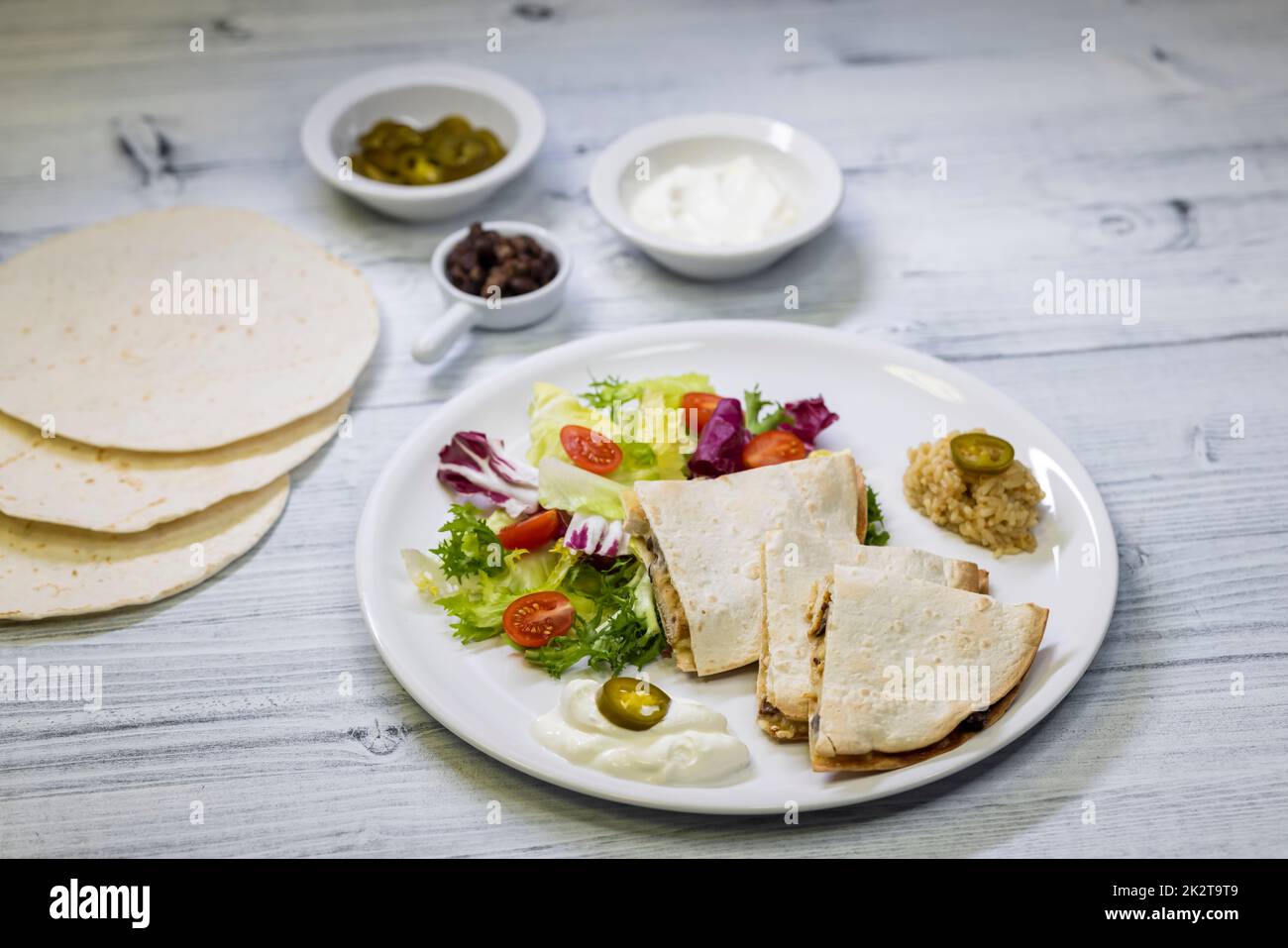 Hühnchen-Quesadilla mit Reis, Bohnen, Salat, Chalapenos und Salsa Stockfoto