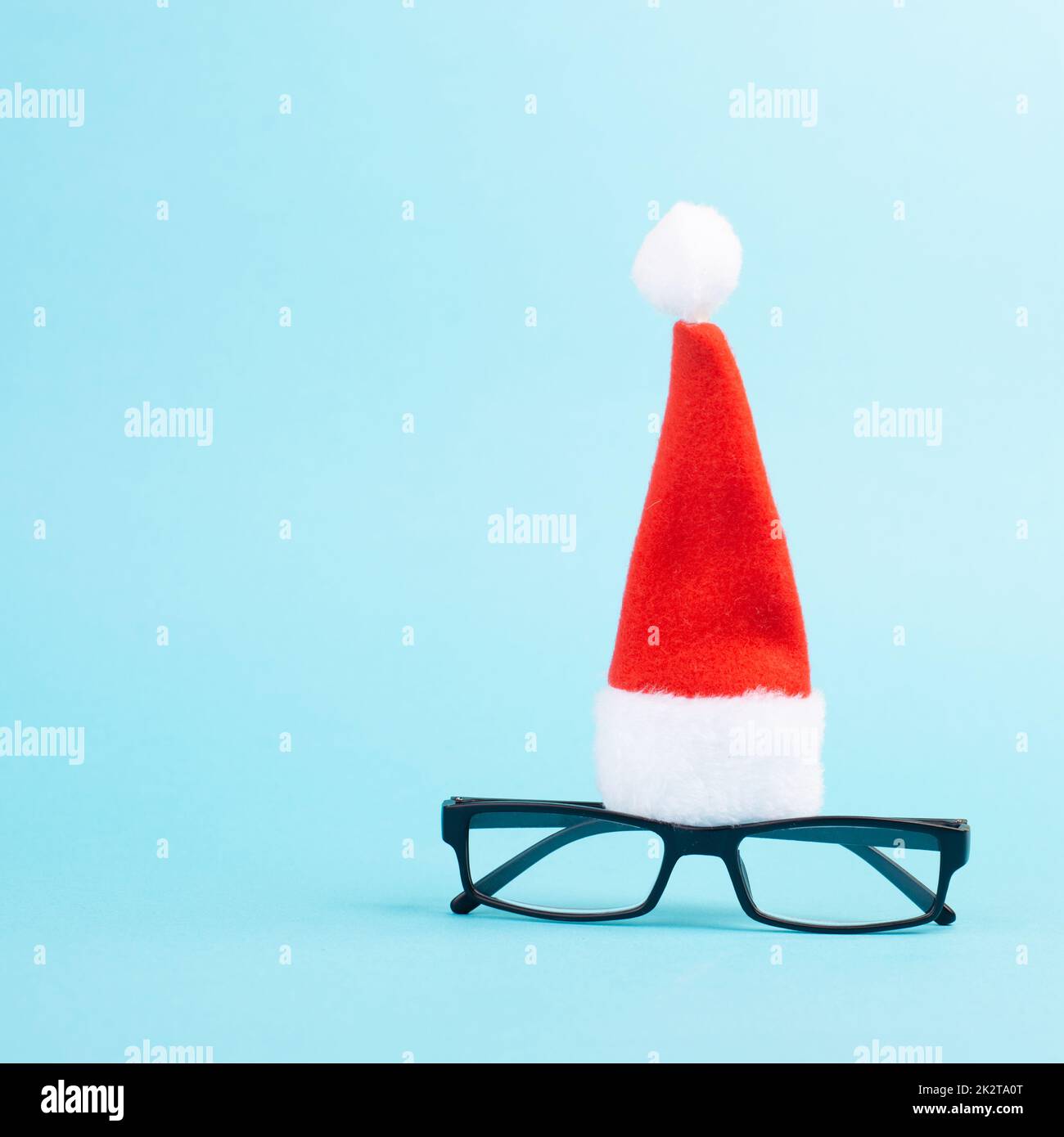 Weihnachtszeit, roter Weihnachtsmann Hut und Brille, lustiges Gesicht, Winterzeit, Weihnachtskarte, blauer Hintergrund Stockfoto