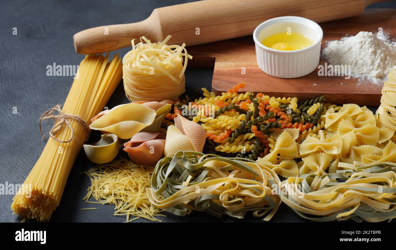 Auswahl an rohen Nudeln. Verschiedene Arten von Makkaroni, Tagliatelle, Farfalle, Spaghetti, Penne rigate . Bunt, rot, grün, gelb, Nudel. Stockfoto