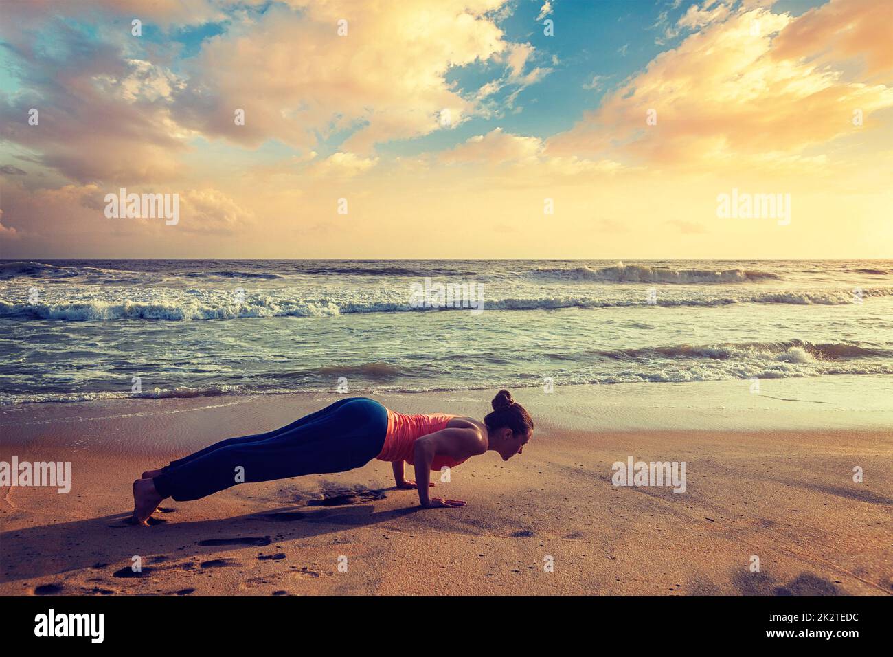 Frau Praktiken Yoga Asana Chaturanga Dandasana am Strand Stockfoto