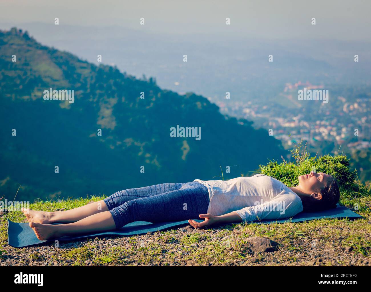 Frau entspannt sich in Yoga Asana Savasana im freien Stockfoto