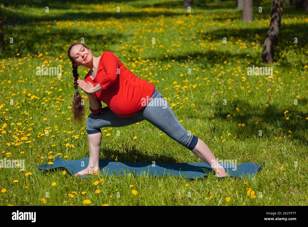 Schwangere Frau tun Asana Utthita Parsvakonasana im freien Stockfoto