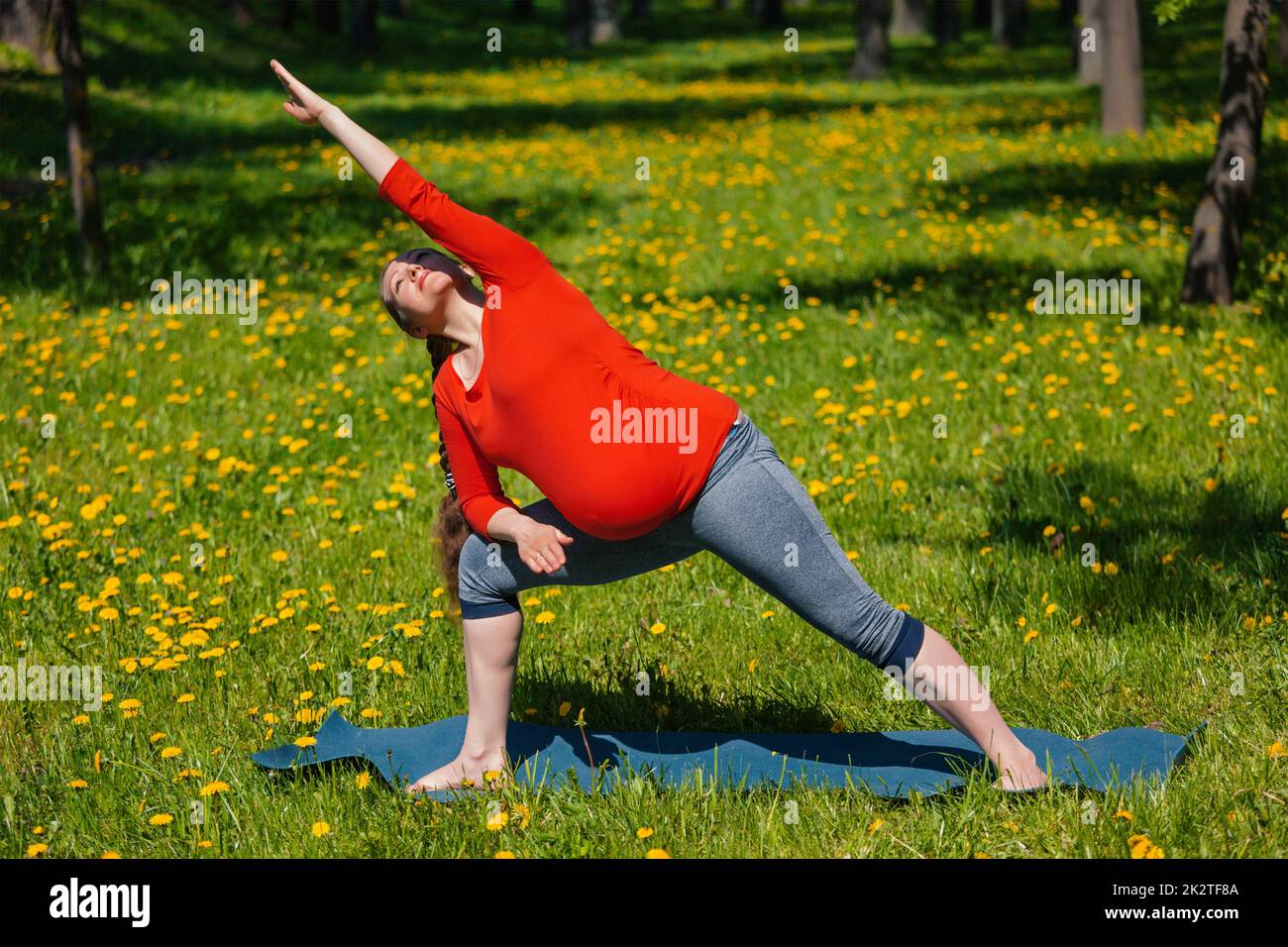 Schwangere Frau tun Asana Utthita Parsvakonasana im freien Stockfoto