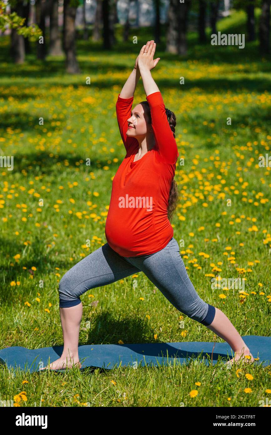 Schwangere Frau tun Asana Virabhadrasana im freien Stockfoto